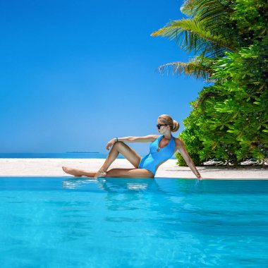 Maldivler tropikal adasındaki havuzda bikinili seksi bir kadın. Havuzda şık bir mayo giymiş göz kamaştırıcı bir manken. Mükemmel vücut bikini modeli. Egzotik bir tur. Lüks seyahat. Seyahat, turizm. Bikini tarzı..