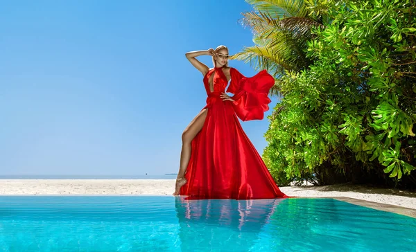 高級ファッションだ エレガントなファッションモデル モルディブのビーチで赤いロングドレスのスタイリッシュな女性モデル 優雅さ プールの近くの素晴らしい赤いドレスを着た上品な女性 クチュール ヴォーグ — ストック写真