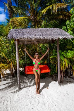 Maldivler adasında bikinili güzel, bronzlaşmış bir kadın. Maldivler sahilinde mayo giymiş çekici bir kız. Maldivler 'deki lüks bir tatil köyünde mükemmel bir vücut bikini modeli. Bikini tarzı. Lüks seyahat.