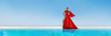 Lüks moda. Zarif bir manken. Maldivler plajında kırmızı uzun elbiseli şık bir kadın manken. Zarafet. Havuzun yanında kırmızı elbiseli klas bir kadın. Özel tasarım. Vogue. Panorama.