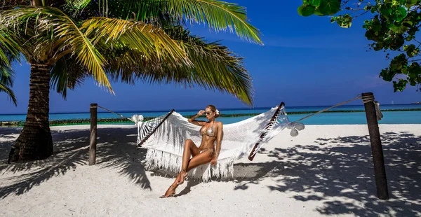 马尔代夫岛上穿着金色比基尼的漂亮性感的晒黑的女人 年轻迷人的姑娘正躺在天堂的吊床上 马尔代夫海滩上完美的比基尼模特 比基尼时装 奢侈旅行 — 图库照片