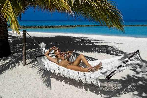 马尔代夫岛上穿着金色比基尼的漂亮性感的晒黑的女人 年轻迷人的姑娘正躺在天堂的吊床上 马尔代夫海滩上完美的比基尼模特 比基尼时装 奢侈旅行 — 图库照片