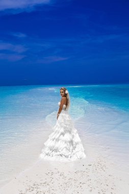 Gelin plajda. Maldivler plajında zarif uzun elbiseler içinde şık bir kadın manken. Zarafet. Maldivler 'de gelin. Gelin modası. Muhteşem fırfırlı beyaz elbiseli şık bir kadın. Lüks seyahat