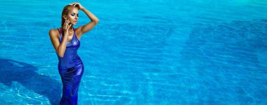 Luxury fashion. Elegant fashion model. Stylish female model in elegant long gown dress is posing in pool on the Maldives. Elegance.  Classy woman in amazing shiny dress in water. Couture.