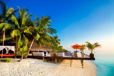 Landscape on Maldives island, luxury water villas resort and wooden pier. Beautiful sky and ocean and beach with palms background for summer vacation holiday and travel concept. Luxury travel.