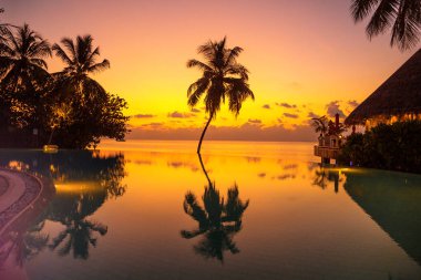 Sunset on Maldives island. Beautiful sky and ocean and beach with palms background for summer vacation holiday and travel concept.