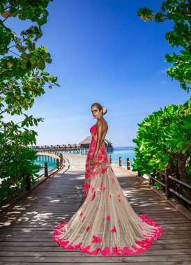 Maldivler kumsalında uzun elbiseler içinde şık bir manken poz veriyor. Zarafet. Özel tasarım. Vogue.