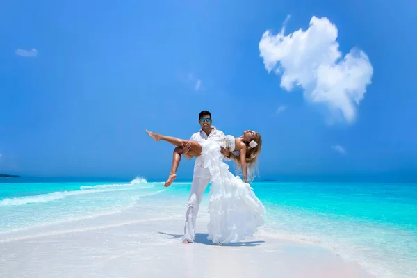 Summer love. Beautiful happy young couple in wedding clothes is standing on a beach in the Maldives. Engagements and wedding on the beach on the paradise island of Maldives. Luxury travel.