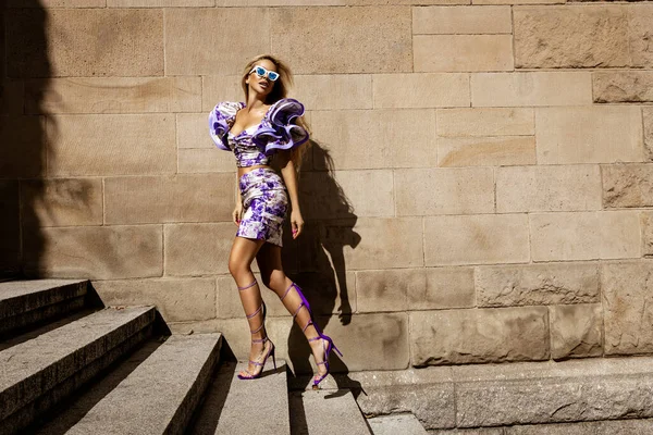 ファッショナブルなライラックドレスとハイヒールでセクシーなモデルが街を歩いています 屋外撮影 — ストック写真