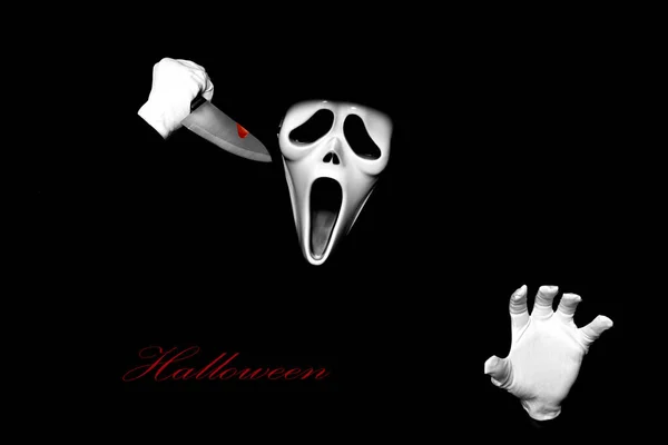 Scream devil costume. Someone in black cover put on white ghost mask on face. Devil cosplay on black background. Funny Halloween costume.