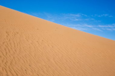Dalgalı kum tepeleri ve mavi gökyüzü arkaplanı. Çöl manzarası, kumlu dalgalar. Doğa. Boşluğu kopyala