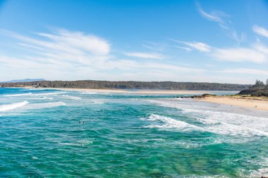 Beyaz köpüklü okyanus dalgaları ve güneşli bir günde kumlu plaj. Doğa tropik cennet arka planı. Tuross Head, NSW, Avustralya