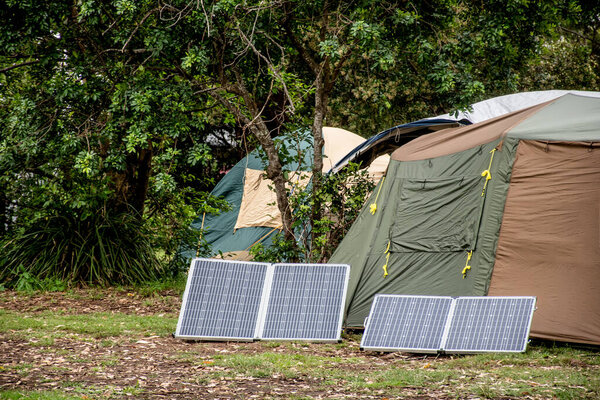 Portable foldable solar panels and Tent at the campsite surrounding by nature. Camping and recreation concept