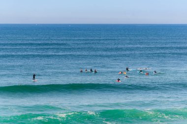 Okyanusta dalgalar bekleyen sörfçüler Cronulla, NSW, Avustralya 'da