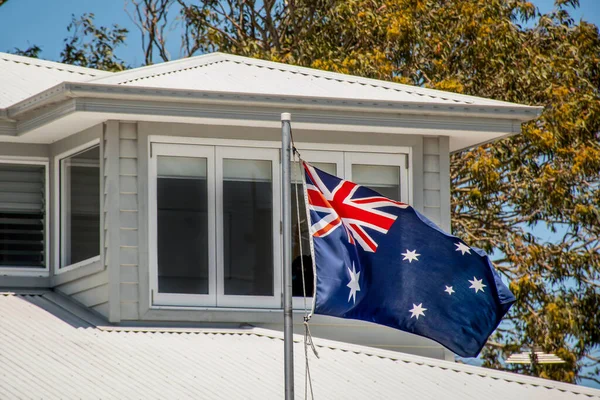 Australian flag blowing in the wind on the resedential building. Australia day celebrations concept