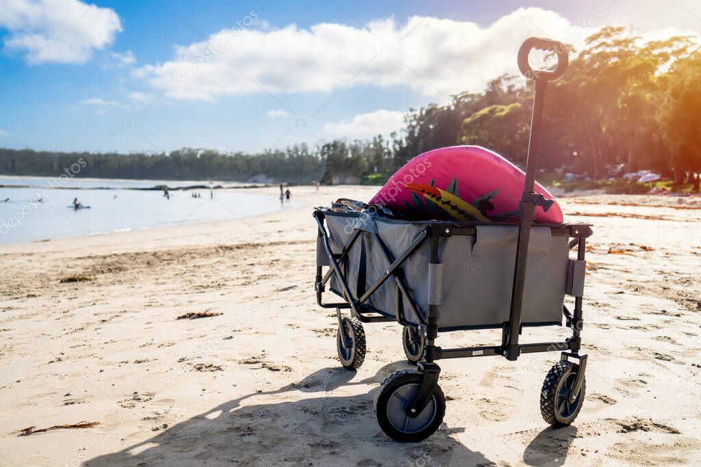 Outdoor beach cart wagon on a sandy beach near the ocean. Family vacation holidays concept