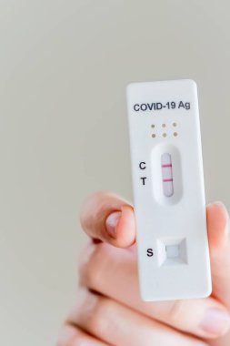 Covid-19 'un hızlı antijen test kasedini tutan eller evde yapılan hızlı tanı testi sonucu pozitif çıktı.