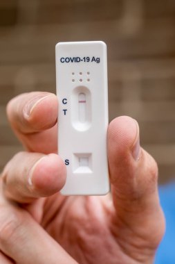 Covid-19 'un hızlı antijen test kasedini tutan eller evde yapılan hızlı teşhis testinin negatif sonucunu içeriyor.