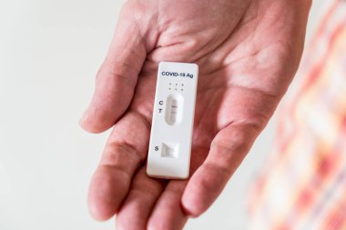 Covid-19 'un hızlı antijen test kasedini tutan eller evde yapılan hızlı tanı testi sonucu pozitif çıktı.