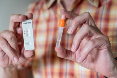 Covid-19 'un hızlı antijen test kitini tutan eller. Numuneli tüp ve test kaseti. Olumsuz sonuç. Evde kendini sınama