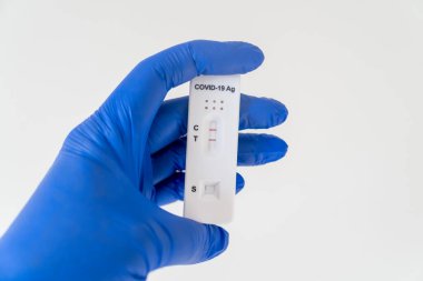 Ellerinde Covid-19 'un hızlı antijen test kasedi olan hemşire eldiveni ve hızlı tanı testi sonucu pozitif çıktı.