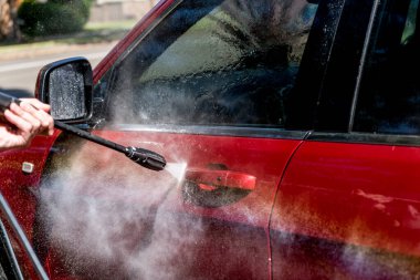 Kırmızı bir SUV 4wd arabayı yüksek basınçlı çamaşır makinesiyle yıkarken seçici odak noktası. Araba yıkama servisi.