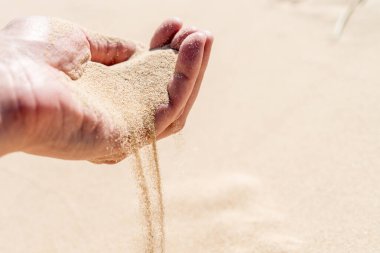 Kum, parlak güneşli bir günde kumlu çöl kum tepelerine dökülüyor. Zamanın geçişi. Seçici odak