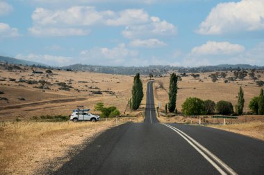 Jindabyne, Avustralya 2019-12-29 Avustralya 'da tarlalar ve tarlalarla çevrili düz yol. Yolculuk konsepti