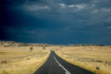 Avustralya 'daki fırtınadan hemen önce tarlalar ve çiftliklerle çevrili boş bir yol. Yolculuk konsepti
