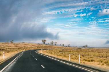 Avustralya 'da çiftlik ve tarlalarla çevrili boş bir yol. Yolculuk konsepti