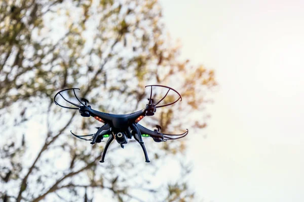 Black drone camera quad copter flying in the blue sky. Drone photography videography aerial wireless technology