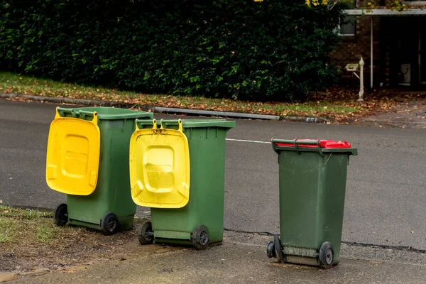 Australian garbage wheelie bins with colourful lids for recycling and general household waste lined up on the street kerbside for council rubbish collection