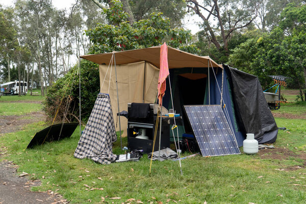 Portable foldable solar panels and Tent at the campsite surrounding by nature. Camping and recreation concept