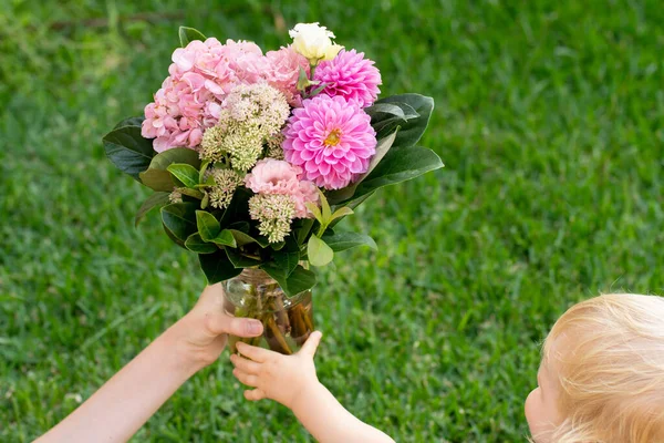 Toddler holding beautiful pink bouquet with dahlia flowers. Mother\'s day gift present congratulations concept