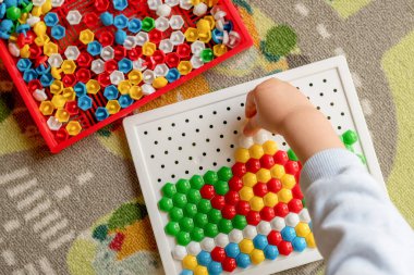 Seçici odaklanma. Yürüyen çocuk tahta mozaiği oynuyor. Erken çocuk gelişimi. Güzel motor beceriler. Öğrenme ve yaratıcılık