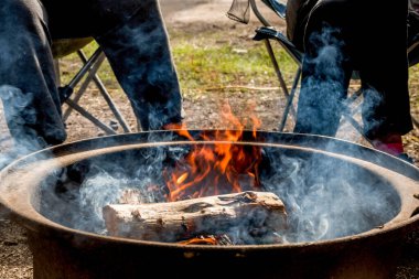 Kamp ateşi yangında yanıyor. İnsanlar oturuyor. Kamp hayatı. Açık hava aile eğlencesi..
