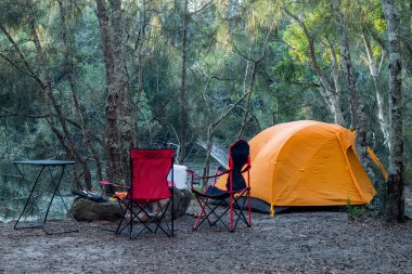 Orange tent on the river bank in the forest. Travel tourism camping life concept