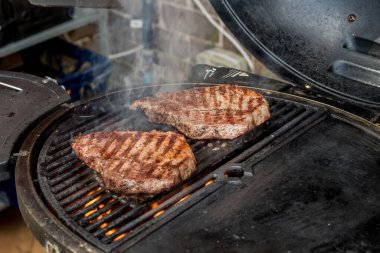 Beef blade steak grilling on barbecue grill plate . Backyard BBQ grill cooking meat.