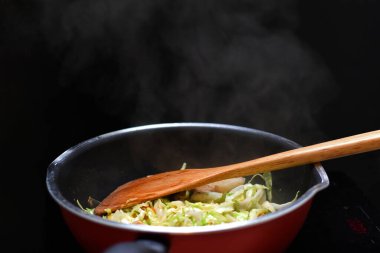 İndüksiyon fırınıyla teflon pan ısı kaynağında karışık sebzeleri karıştır.