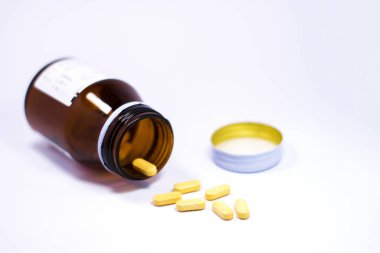 İlaç şişesi beyaz arka plana ilaç ya da vitamin döküyor..