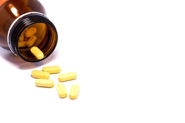 İlaç şişesi beyaz arka plana ilaç ya da vitamin döküyor..