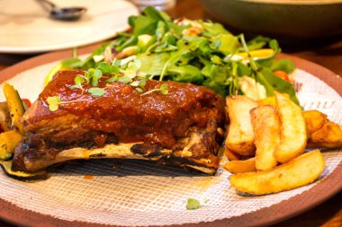 Kızarmış patates ve sebzeli barbekü soslu domuz pirzolası..