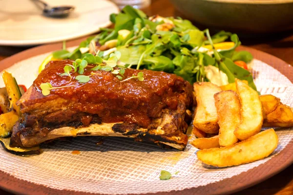 Kızarmış patates ve sebzeli barbekü soslu domuz pirzolası..