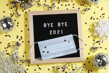 Sarı arka planda süsleme ve maskeyle veda mesajı içeren siyah harf tahtası. Mutlu yeni kulak 2022 konsepti.