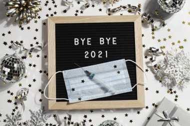 Siyah harfli pano, beyaz arka planda süsleme, şırınga ve maskeyle veda mesajı 2021. Mutlu yeni kulak 2022 konsepti.