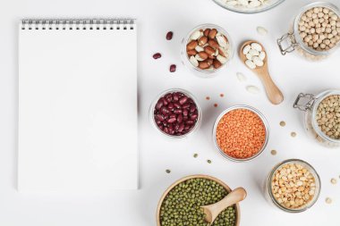 Vegan protein kaynağı. Fasulye, bezelye, nohut, mercimek, fasulye, beyaz arka planda fıstık, not defteri. Sağlıklı vejetaryen yemekleri. Boşluğu kopyala