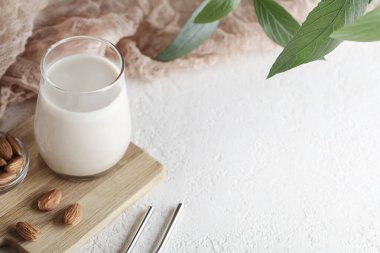 Bardakta vejetaryen badem sütü, fındıklı ve beyaz arka planda bitki. Uzayı kopyala Sağlıklı vejetaryen yemekleri. Seçici odaklanma. Sütsüz alternatif süt