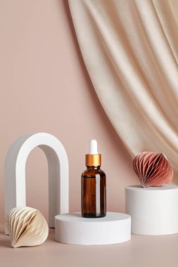 Podyum sahnesinde serum esansı, bej arka planda geometrik kemerler, tekstil ve bal peteği dekoru. Tatil kavramında cilt kozmetiği