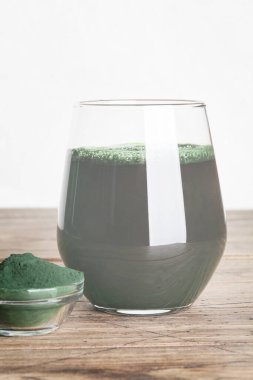 Taze yeşil içecek, camda spirulina, ahşap zemin üzerinde kaşık olan spirulina tozu. kullanışlı alışkanlıklar