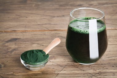 Taze yeşil içecek, camda spirulina, ahşap zemin üzerinde kaşık olan spirulina tozu. kullanışlı alışkanlıklar